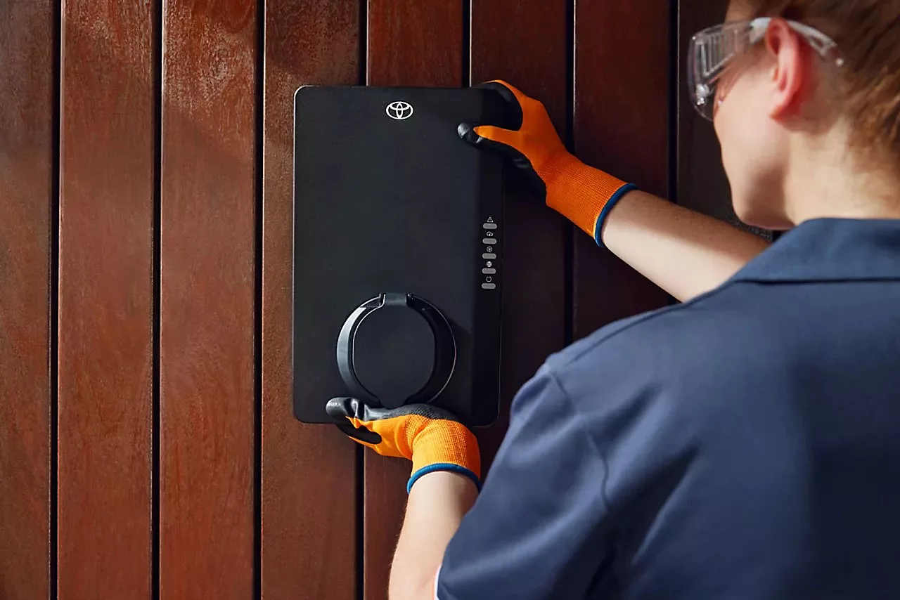 Fachkraft montiert eine Toyota Wallbox an einer Holzverkleidung – Installation einer Ladestation für Elektroautos, E-Mobilität zu Hause, sicheres und effizientes Laden mit Toyota-Technologie.