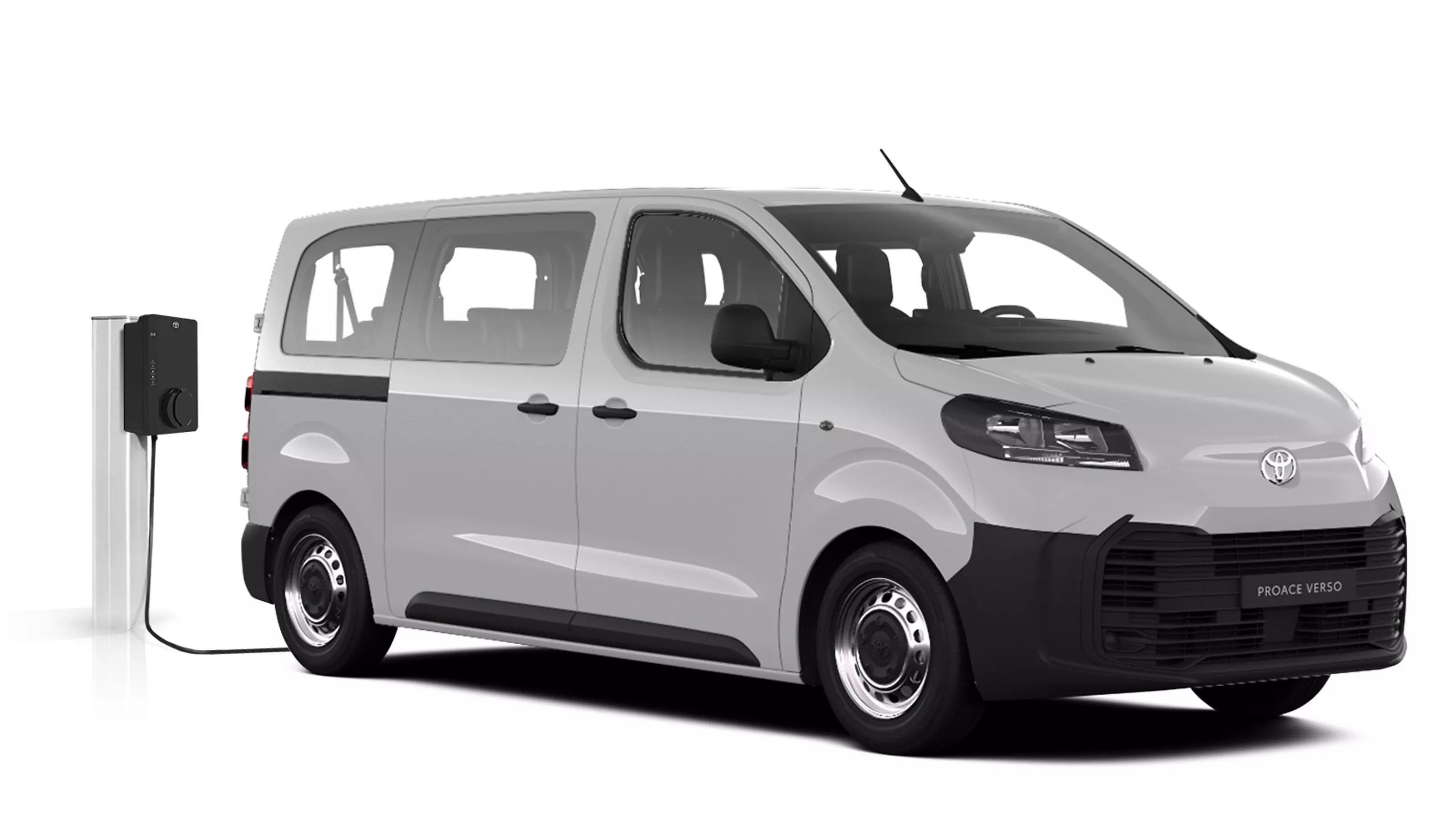 Weißer Toyota Proace Verso Electric steht diagonal zur Kamera vor neutralem Hintergrund neben einer Ladesäule.