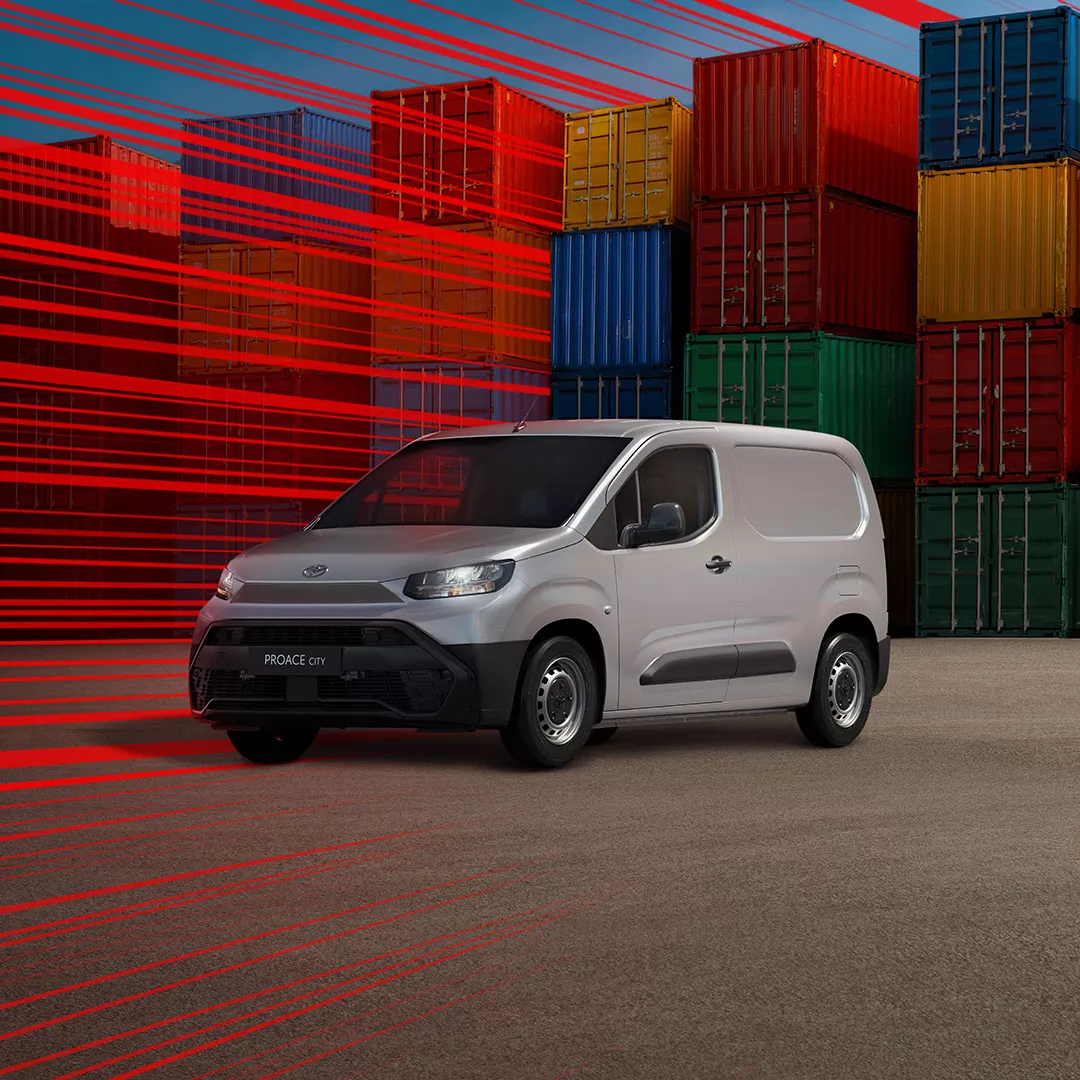 Eine Person vor einem Gewächshaus läuft auf die Fahrertür eines grauen Proace City zu.