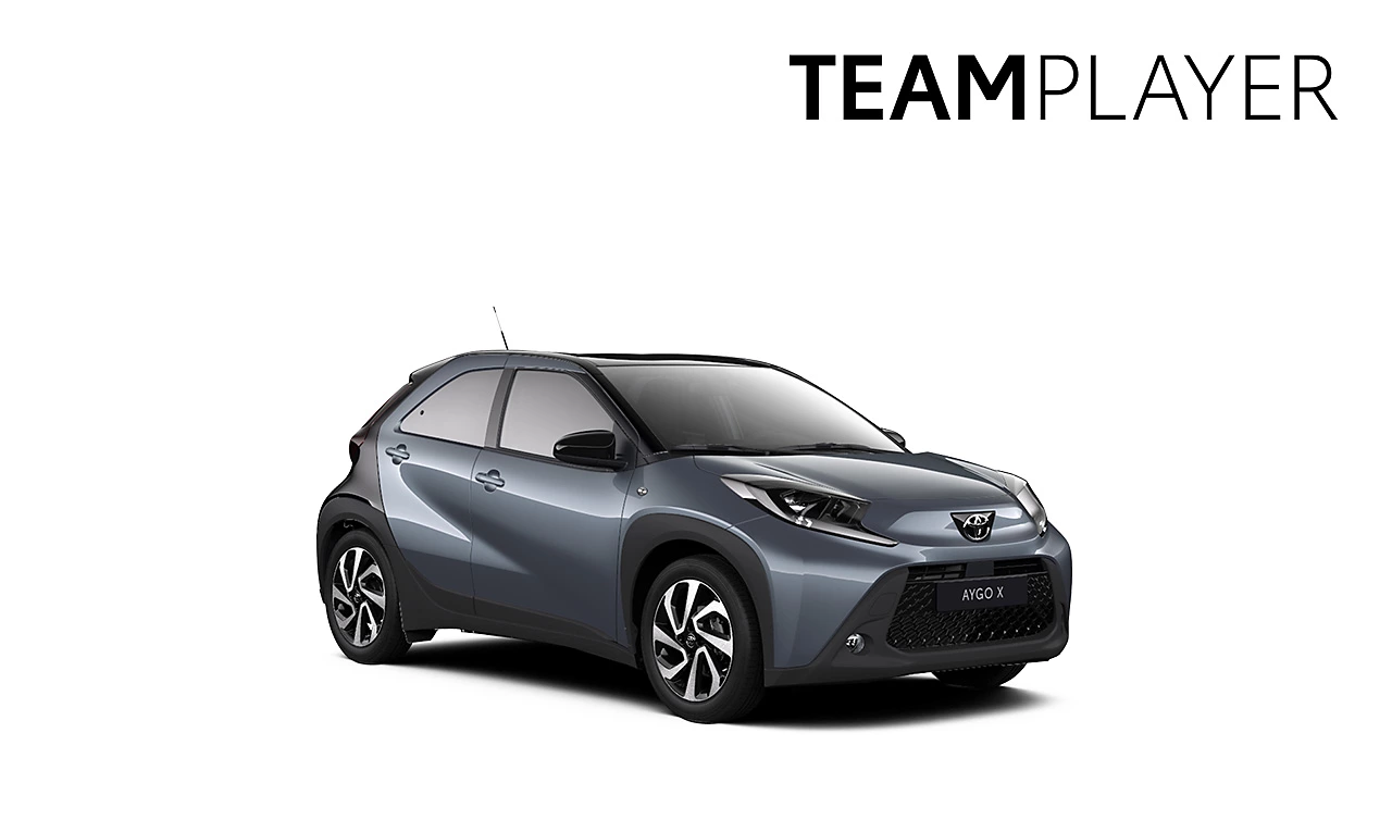 Der dunkelblau schwarze Toyota Aygo X in diagonaler Frontansicht vor einem weißen Hintergrund und dem Logo mit der Schrift "Teamplayer" in der oberen rechten Ecke